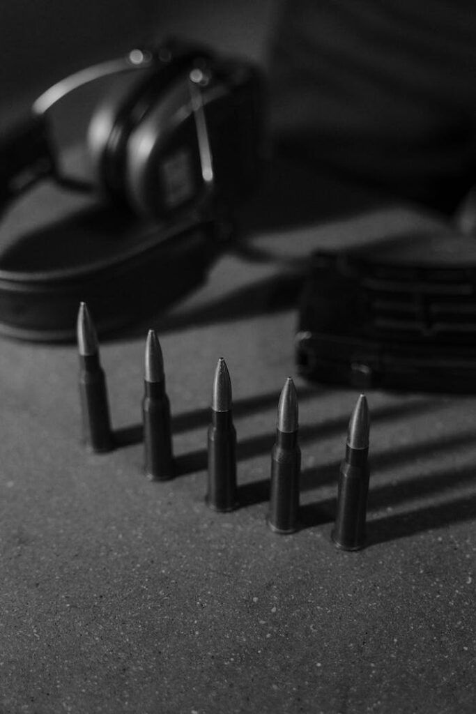 Monochrome image of bullets, headphones, and magazine on a concrete surface.
